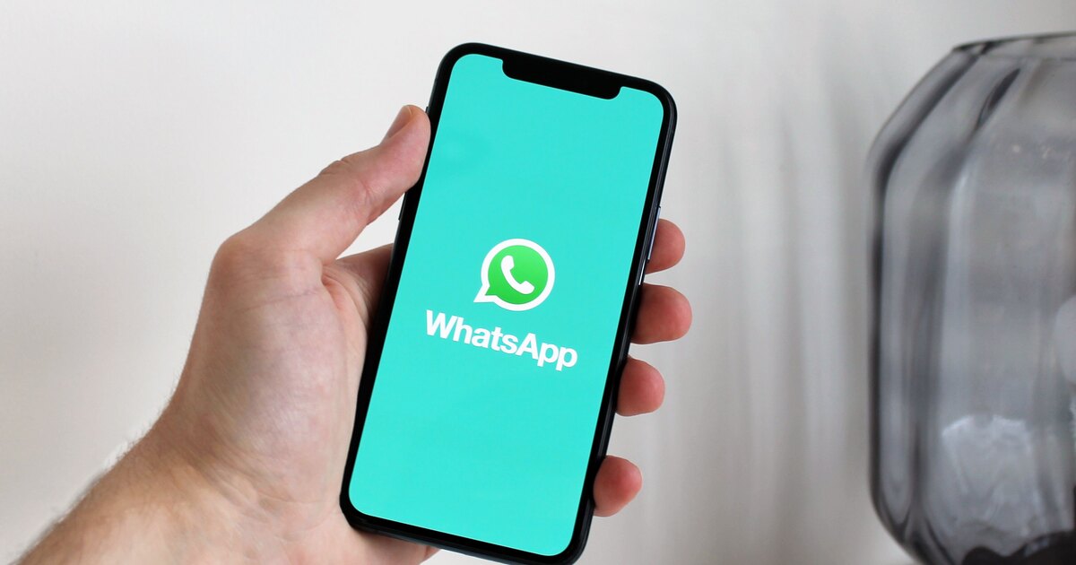 Mano sosteniendo un móvil con una conversación de WhatsApp