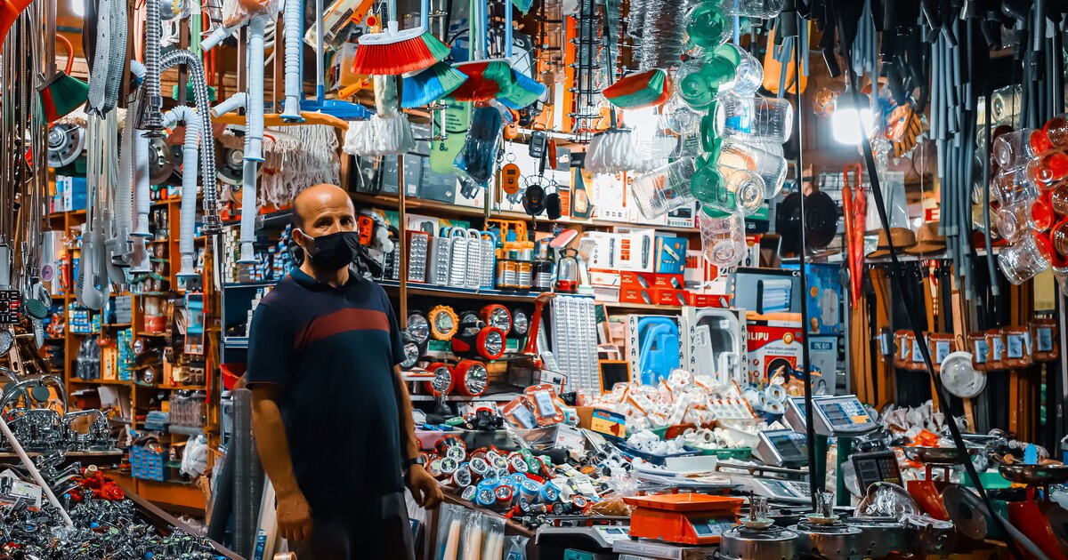 Mostrador de una ferretería con productos en las estanterías y atención a un cliente